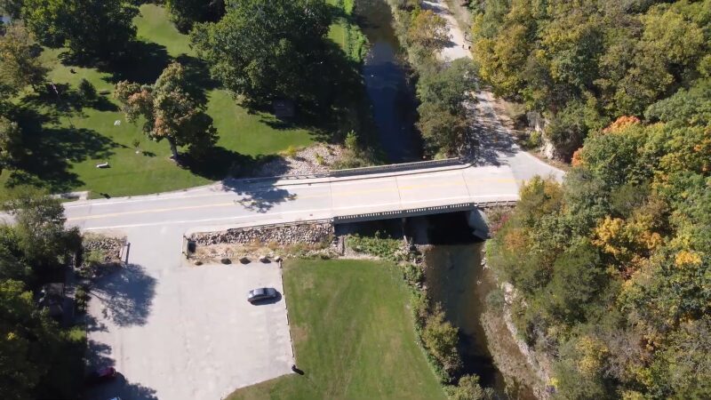 An Aerial View of A Bridge Over a Small River Surrounded by Lush Trees, with Nearby Parking and Green Spaces, Illustrating the Amenities Available for Anglers at Apple Canyon Lake