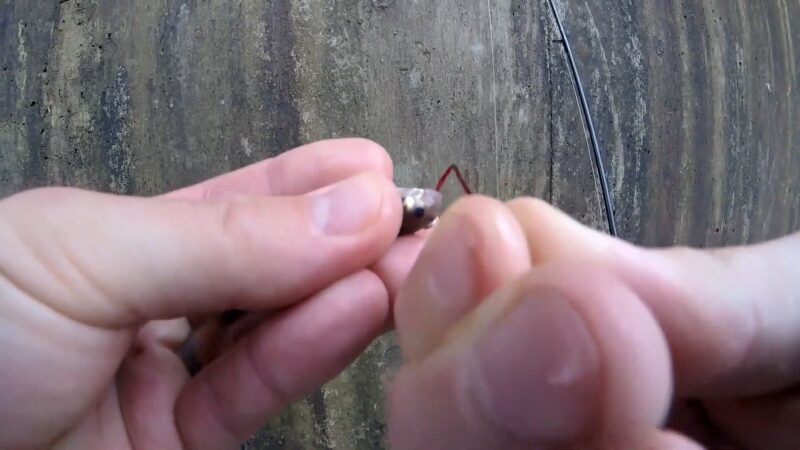 Hands Carefully Hook a Live Minnow Against a Textured, Worn Surface for Bluegill Fishing