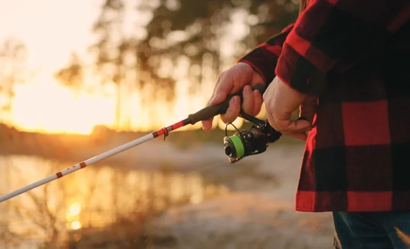 Man holding fishing stick during a sunset