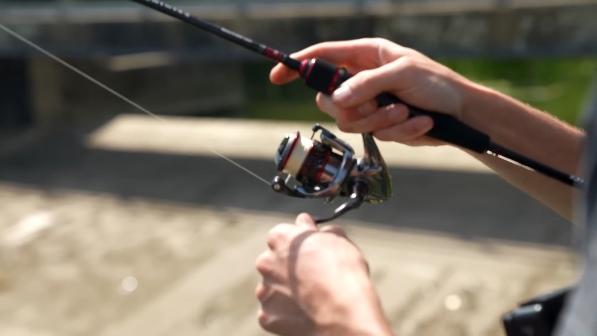 Close-up of a person’s hands holding a fishing rod with a spinning reel, preparing to cast the fishing line